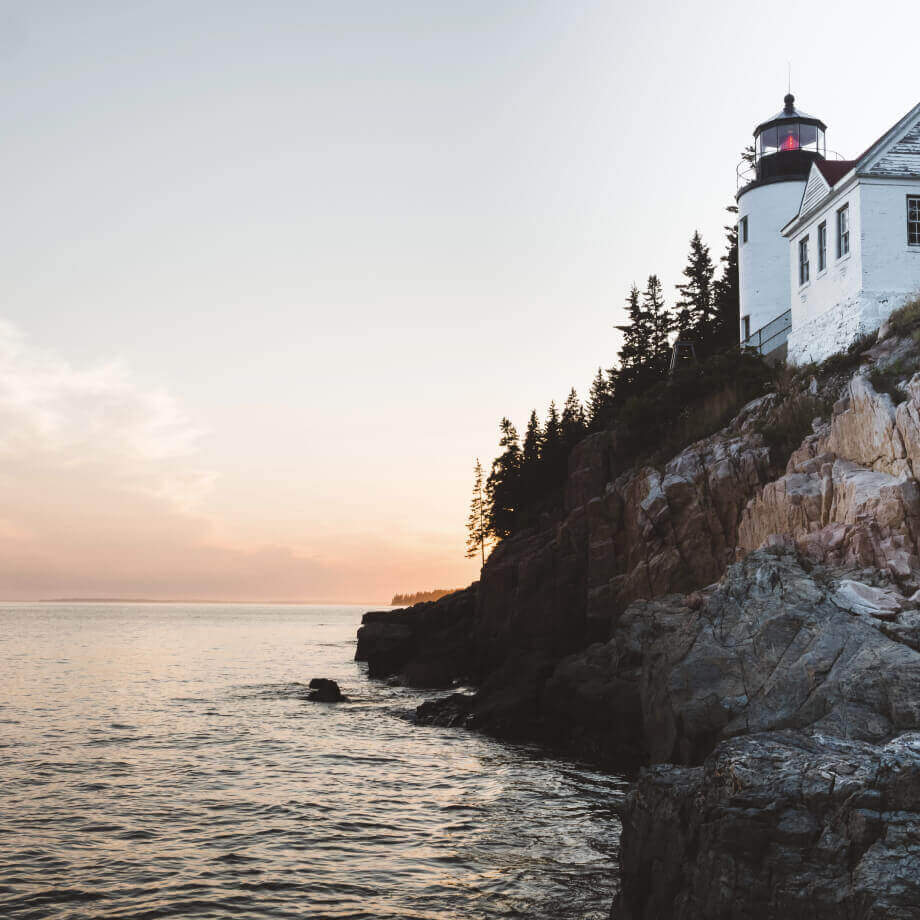 a lighthouse on the edge of a cliff next to the sea